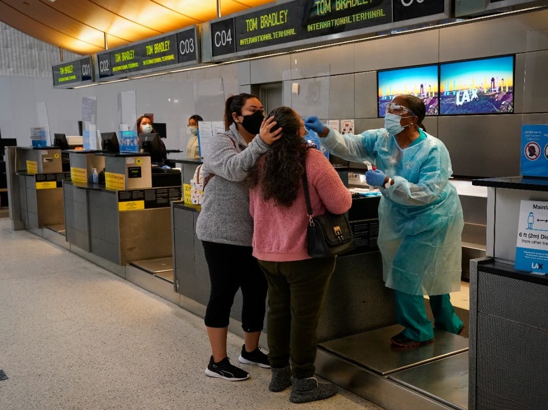 File Photo: Licensed vocational nurse Caren Williams, right, collects a nasal swab sample from a traveler at a COVID-19 testing site at the Los Angeles International Airport in Los Angeles