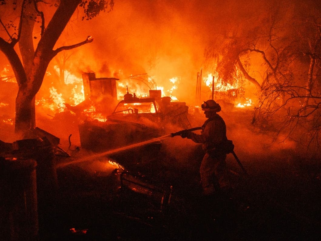 A firefighter takes a hose to a burning property while battling the Fairview Fire Monday, Sept. 5, 2022, near Hemet, Calif.