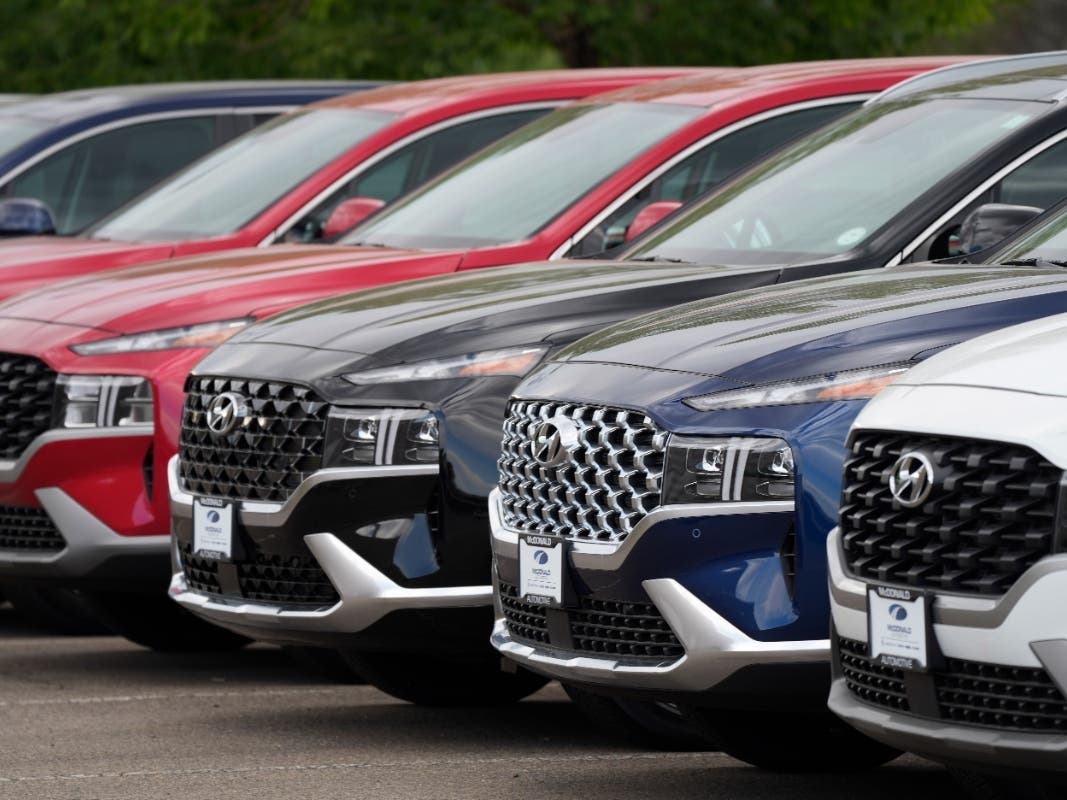 A line of 2022 Santa Fe SUVs sit outside a Hyundai dealership.