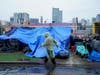 Homeless people use plastic tarps to shield themselves from a light rain brought by Tropical Storm Hilary in downtown San Diego, Sunday, Aug. 20, 2023. 