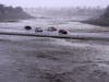 Vehicles cross over a flood control basin that has almost reached the street, Sunday, Aug. 20, 2023, in Palm Desert, Calif. Forecasters said Tropical Storm Hilary was the first tropical storm to hit Southern California in 84 years.