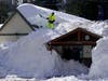A worker clears snow off the roof of Skyforest Elks Lodge after a series of storms, Wednesday, March 8, 2023, in Rimforest, Calif. 