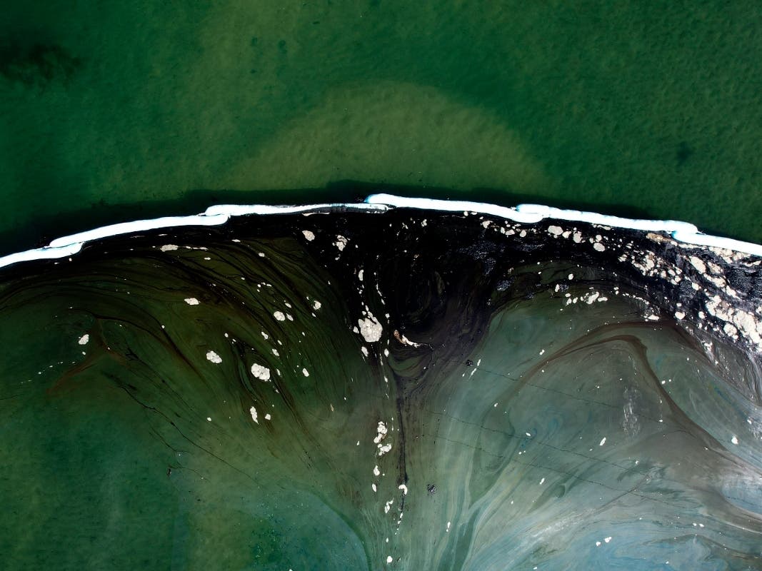 An aerial file photo shows floating barriers known as booms set up after an oil spill in Huntington Beach in 2021. Federal regulators on Dec. 5, 2023, concluded the rupture of an undersea oil pipeline was likely caused by the proximity of anchored ship.