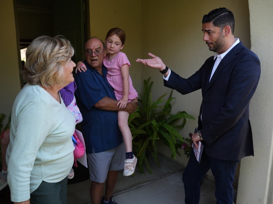 Ammar Campa-Najjar, right, a Democratic candidate for California's 48th Congressional District, speaks with a family as he canvasses in a neighborhood Saturday, May 23, 2026, in San Marcos, Calif. 