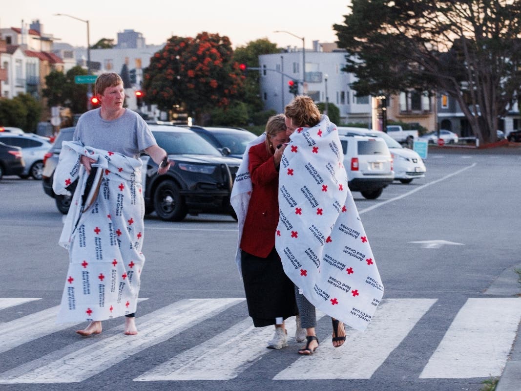 People cover themselves with American Red Cross blankets at Fort Mason, where the Red Cross has set up an assistance center for people impacted by a boat incident in the waters off San Francisco Tuesday, July 14, 2026.