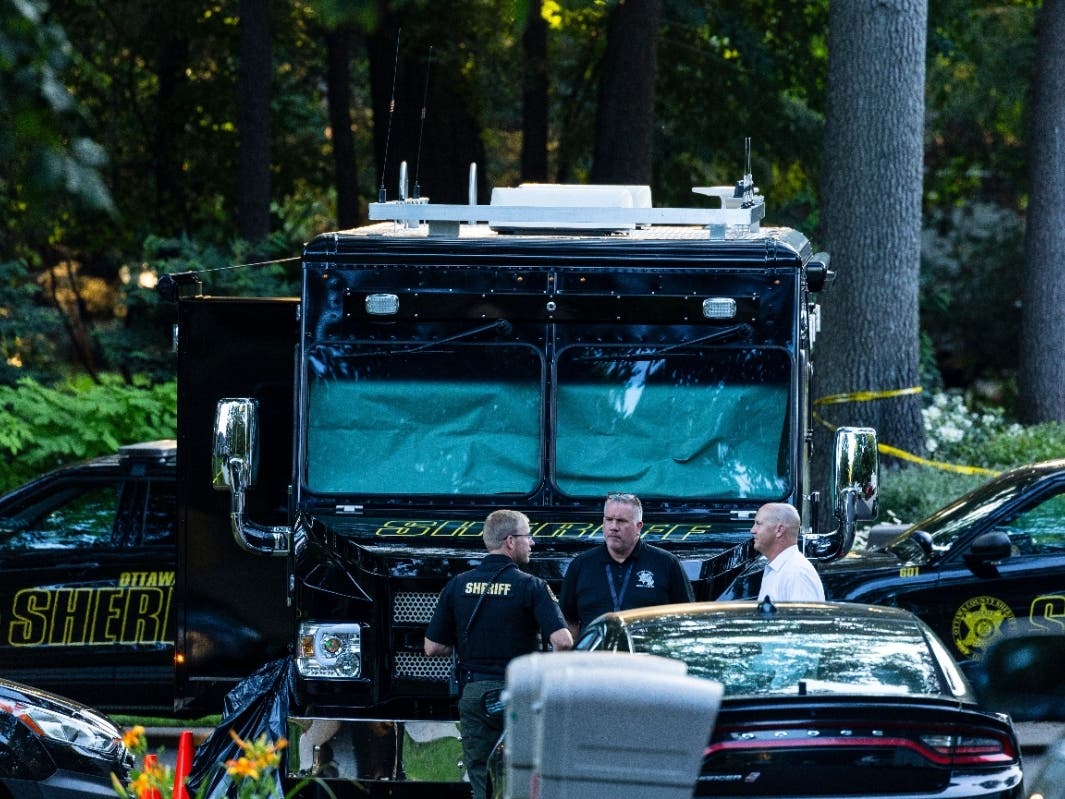 Law enforcement officials gather to investigate a fatal house fire on Friday, July 24, 2026, in Grand Haven Township, Mich. Ottawa County Sheriff's Office said six children and two adults were found dead in a "suspicious" house fire