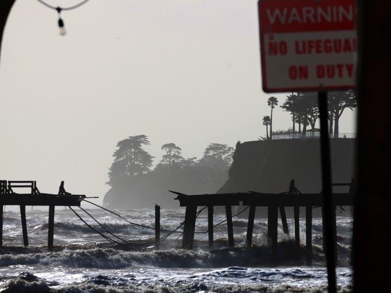 Waves in the Monterey Bay batter the storm-damaged Capitola Wharf in Capitola, Calif., Tuesday, Jan. 10, 2023. The Wharf is seen through a passageway on the Capitola Esplanade.