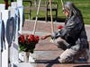 Lisa Lozano touches roses in front of wooden hearts with messages on them at a makeshift memorial in front of the Monterey Park City Hall in Monterey Park, Calif., Tuesday, Jan. 24, 2023.