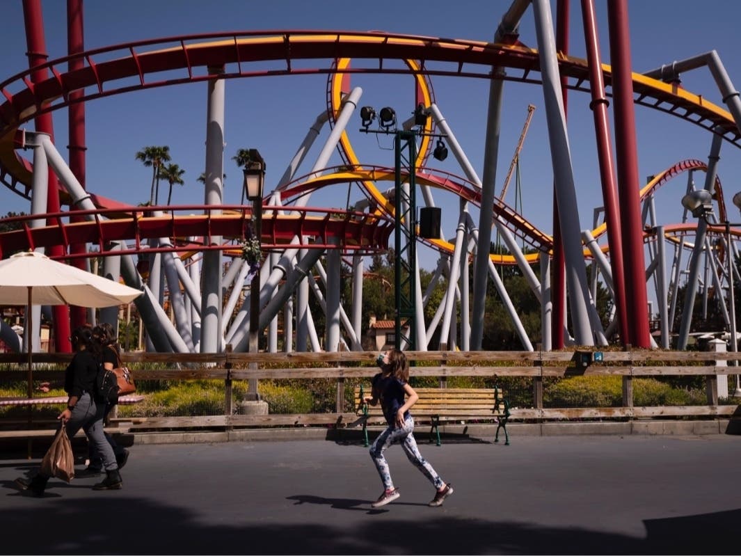 A young visitor runs past a ride to catch up with her family during the Knott's Taste of Boysenberry Festival at Knott's Berry Farm in Buena Park, Calif., Tuesday, March 30, 2021.
