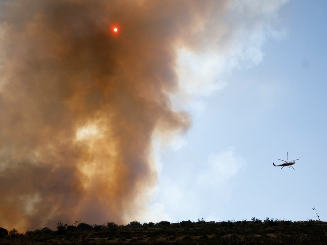 A helicopter flies past the Sandy Fire, Tuesday, May 19, 2026, in Simi Valley, Calif.
