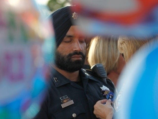 In this Aug. 29, 2015, photo, Harris County Sheriff's deputy Sandeep Dhaliwal gets a blue ribbon pinned to him during a vigil at the Chevron station in Houston where another deputy was fatally shot.
