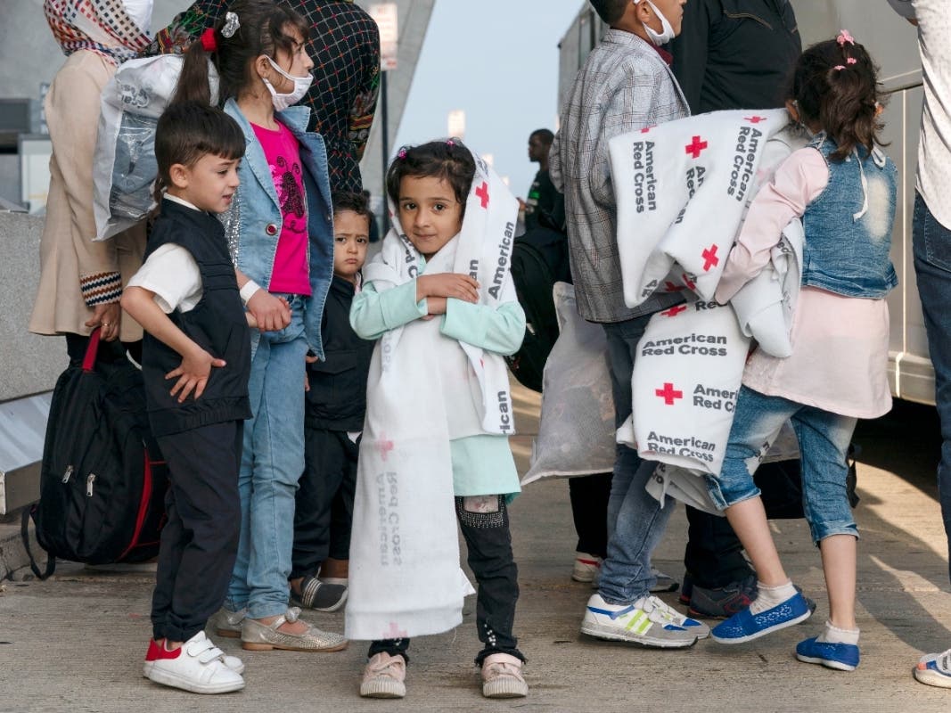 Families evacuated from Kabul, Afghanistan, wait to board a bus after they arrived at Washington Dulles International Airport, in Chantilly, Va., on Thursday, Aug. 26, 2021. 