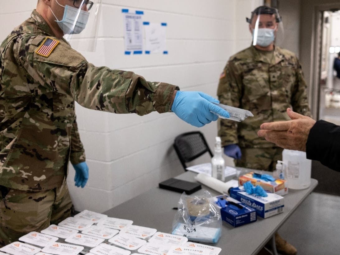 Minnesota National Guard Sgt. Hudak (L) hands out self-administered spit tests at a COVID-19 testing facility in the Stillwater Armory National Guard Center on December 10, 2020 in Stillwater, Minnesota.