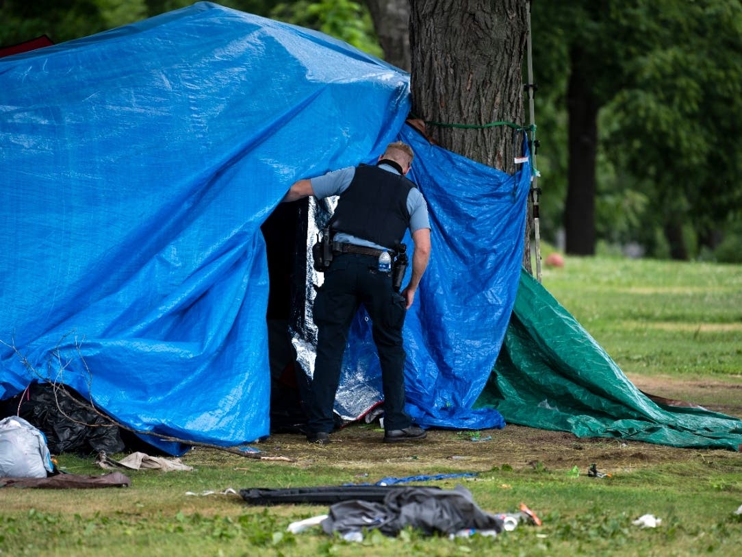 A Minneapolis Police officer checks a structure in Powderhorn Park before clearing it to be destroyed as a homeless encampment is cleared on July 20, 2020, in Minneapolis, Minnesota.