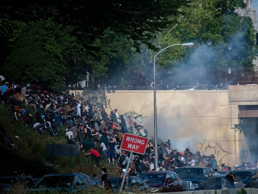 Protesters race up a hill after being shot by tear gas after a march through Center City on June 1, 2020 in Philadelphia, Pennsylvania.