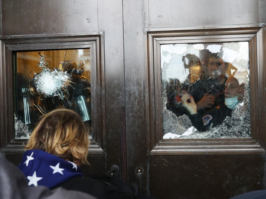 A Capitol police officer looks out of a broken window as rioters gather at the U.S. Capitol Jan. 6 in Washington, D.C. 