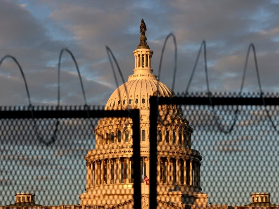 The U.S. Capitol is seen behind a fence with razor wire during sunrise on Jan. 16. After last week's riots at the U.S. Capitol Building, the FBI has warned of additional threats in the nation's capital and in all 50 states.