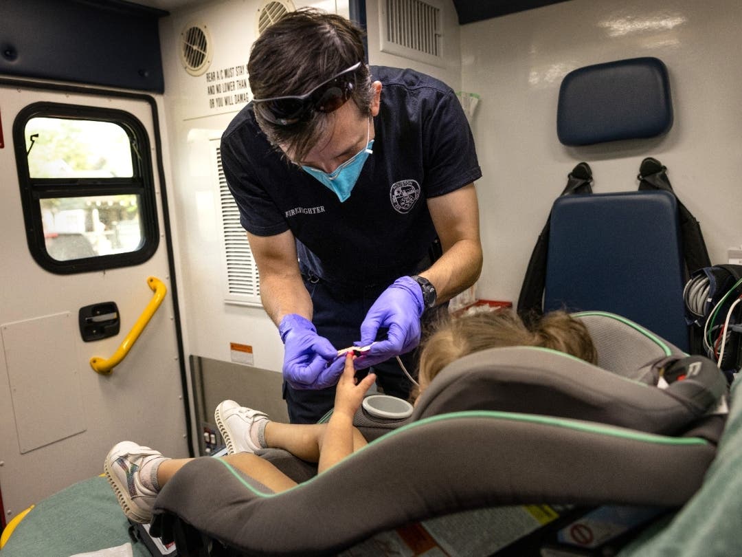 An EMS medic prepares to transport a COVID-19 positive 2-year-old girl who developed symptoms after attending day care amid the delta surge. According to IDPH, the number of coronavirus cases detected among children rose to an all-time high this month.