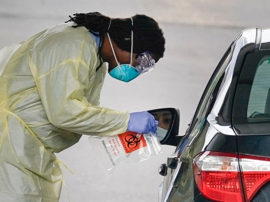 A healthcare worker screens a patient for COVID-19 at a drive-through coronavirus testing site in Arlington, Virginia.
