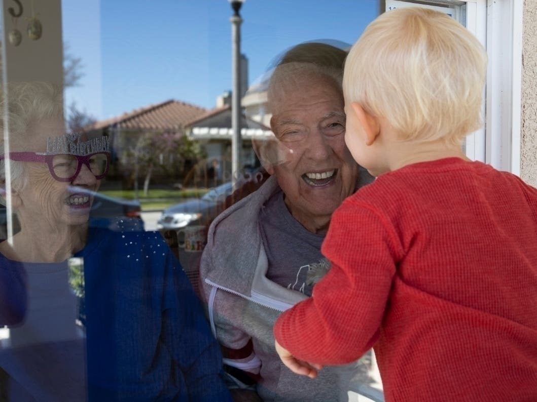 Mary-Lou McCullagh, 83, and her husband Bob, 84, greet Axel Stirton, 2, the little boy who lives across the street April 3, 2020 in Ventura, CA. Mary-Lou and Bob are in isolation, trying to ensure that they do not come in contact with the coronavirus.