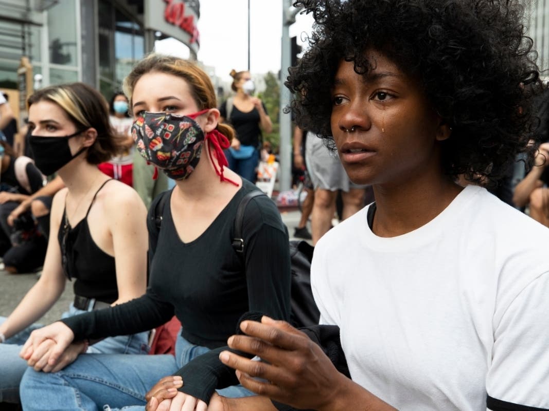 Demonstrators sit holding hands during a march in response to George Floyd's death on June 2, 2020 in Los Angeles, California.