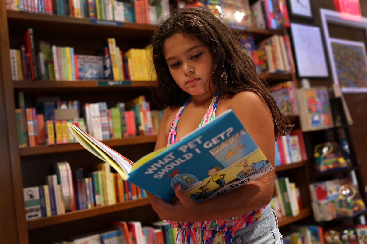 A young girl reads a Dr. Seuss book.