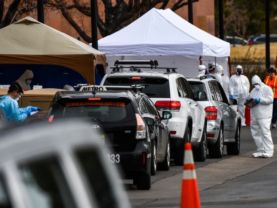 Healthcare workers from the Colorado Department of Public Health and Environment test people for COVID-19 at the state's first drive-up testing center in Denver.