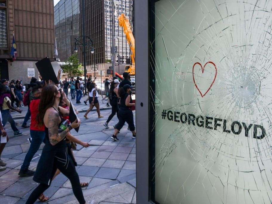 Thousands of people march past a broken sign on the 16th Street Mall as they protest the death of George Floyd.