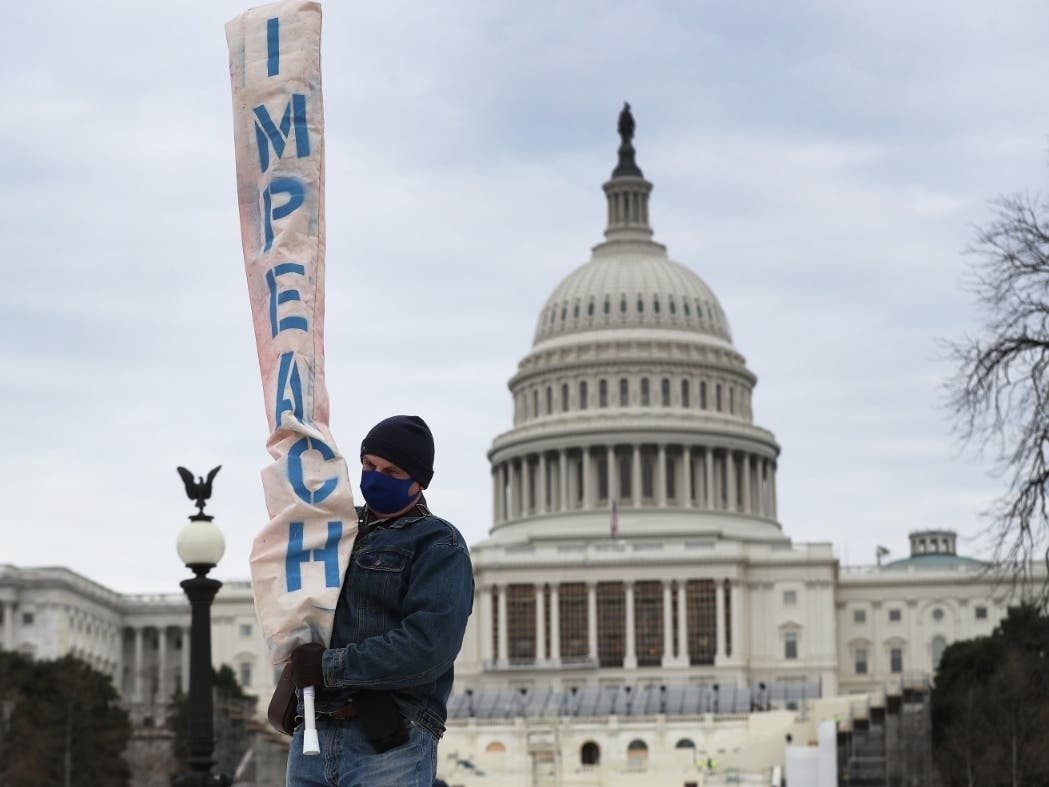 A man carries a banner near the U.S. Capitol Building after a pro-Trump mob broke into the building. Democratic congressional leaders say President Donald Trump encouraged the mob to storm the Capitol.