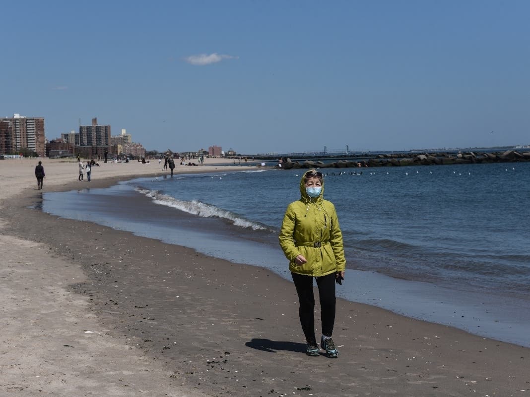 A person walks on the beach while wearing a protective mask on May 13, 2020 in the Coney Island neighborhood in the Brooklyn borough in New York City.