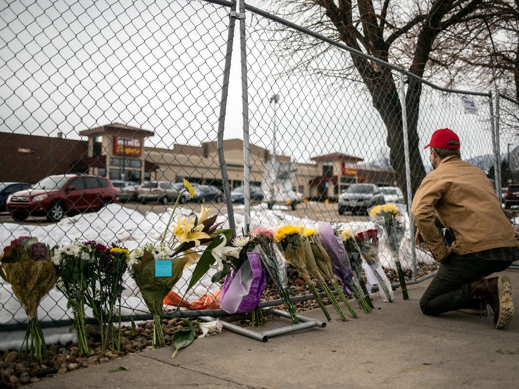 A mourner leaves flowers and pays tribute Tuesday morning after a gunman opened fire at a King Sooper's grocery store in Boulder, Colorado. Ten people were killed.