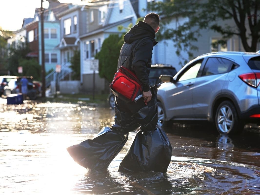 A man uses garbage bags to keep his pants and feet try as he crosses Lester Street in Passaic a day after the remnants of Hurricane Ida moved through.