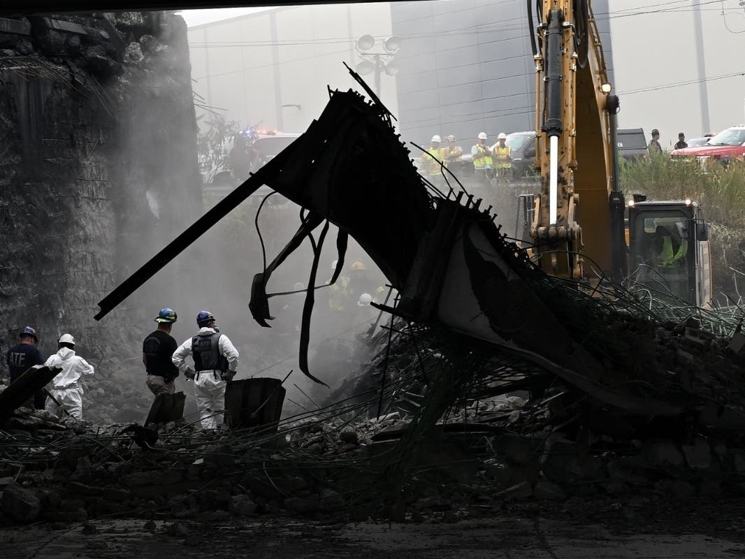 Workers inspect and clear debris from a section of the bridge that collapsed on Interstate 95 after an oil tanker explosion Sunday in Philadelphia.