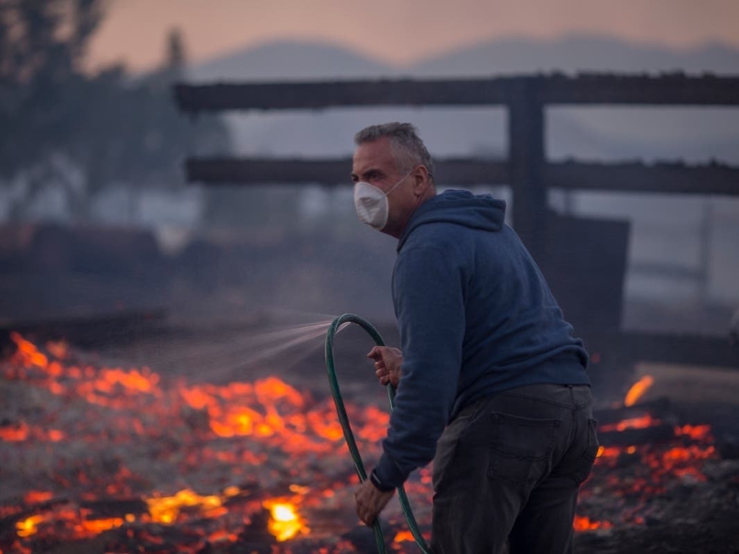 Photo: A resident holds a leaking hose on his burning property during the Creek Fire on December 5, 2017 in Sunland, California. Strong Santa Ana winds are rapidly pushing multiple wildfires across the region, expanding across tens of thousands of acres.