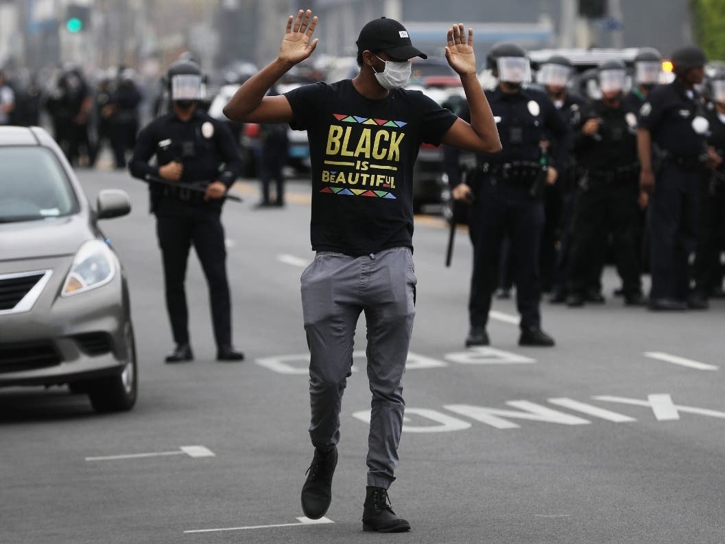 Protesters assist a man who was knocked down during demonstrations following the death of George Floyd on May 30, 2020 in Los Angeles, California.