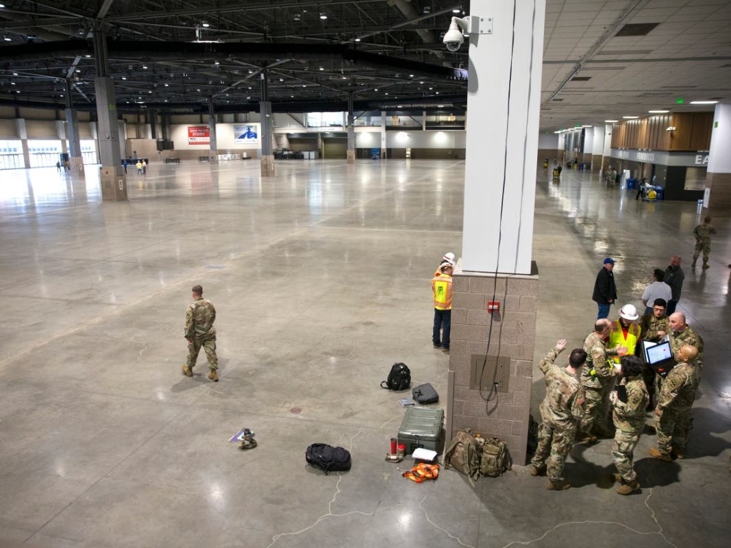 Military personnel and construction workers gather inside the CenturyLink Field Event Center on March 28, 2020 in Seattle. A 150-bed field hospital will be built at the event center, to make room in local hospitals for COVID-19 patients.