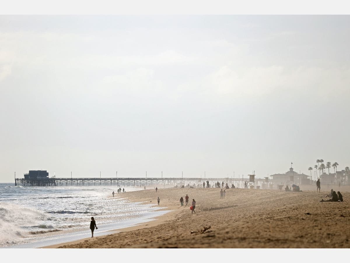 People are seen on the Balboa Peninsula Beach on April 11, 2020 in Newport Beach, California. Many beaches and public spaces across California have been closed to help decrease the spread of COVID-19 and promote social distancing.