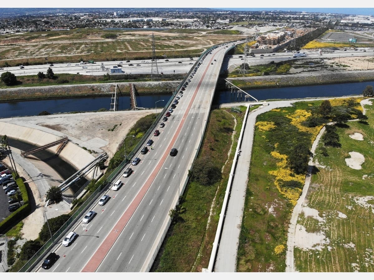 An aerial drone view of cars lined up to receive food distributed by the Los Angeles Regional Food Bank, with light traffic on the 405 freeway below the overpass, amidst the coronavirus pandemic on April 18, 2020 in Carson, California.
