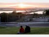 People sit on a hillside overlooking oil pumpjacks at the Huntington Beach Oil Fields on April 20 in Huntington Beach, CA. Oil prices traded in negative territory for the first time as the spread of coronavirus impacts global demand.
