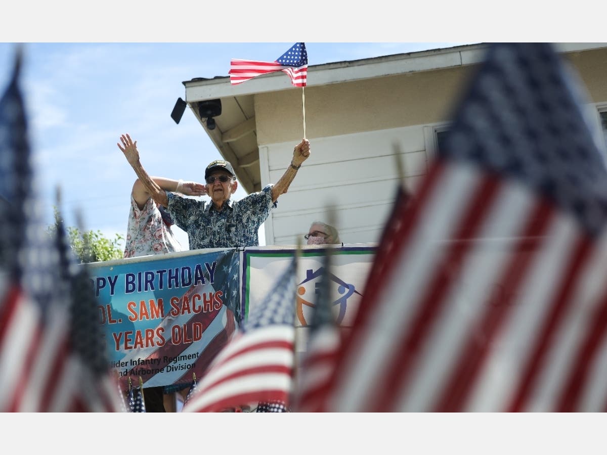 U.S. Army World War II veteran Lt. Colonel Sam Sachs, who turned 105 Sunday, holds an American flag at his drive-by birthday party amid the coronavirus pandemic on April 26 in Lakewood, Callifornia.