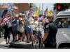  A San Diego Police Department officer looks on as protestors hold banners and chant against state government measures intended to defend against the COVID-19 virus during an Open California rally on April 26, 2020 in San Diego, California.