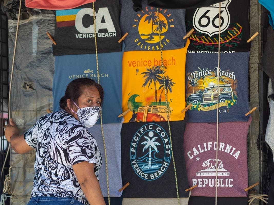 A woman opens a souvenir shirt shop as holiday beach-goers head to Venice Beach on Memorial Day as coronavirus safety restrictions continue being relaxed in Los Angeles County and nationwide on May 24, 2020 in Los Angeles, California. 