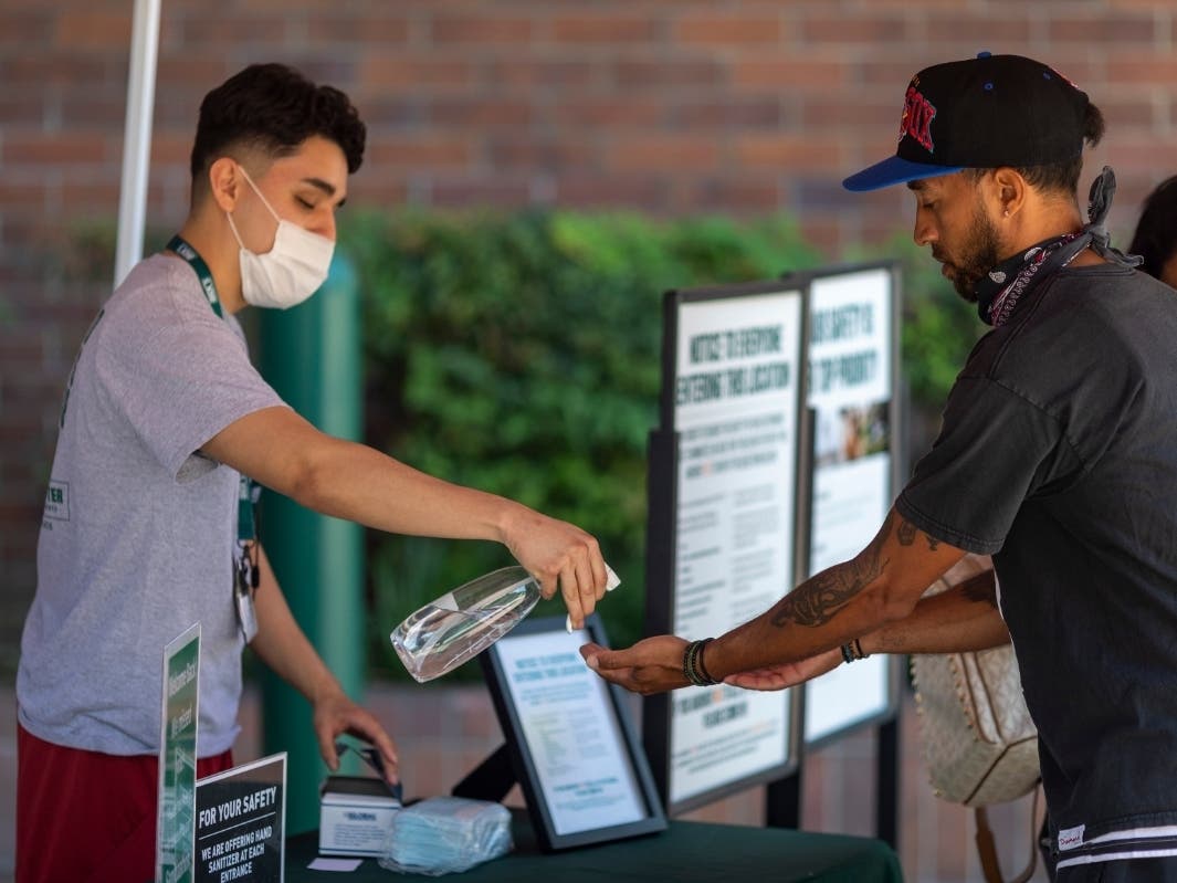 Masks and hand sanitizer are given to customers entering a Dick's Sporting Goods store as Los Angeles County retail businesses reopen while the COVID-19 pandemic continues on May 27, 2020 in Glendale, California.