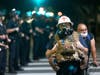 A protest medic walks near police as demonstrations continue over the killing of George Floyd despite the dangers of the widening coronavirus (COVID-19) pandemic on June 6, 2020 in Los Angeles, United States.