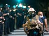 A protest medic walks near police as demonstrations continue over the killing of George Floyd despite the dangers of the widening coronavirus (COVID-19) pandemic on June 6, 2020 in Los Angeles, United States.