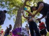 A woman attaches balloons and a man lights candles at the tree that authorities say Robert Fuller, a 24-year-old black man, was found hanging dead from near Palmdale City Hall on June 13, 2020 in Palmdale, California.