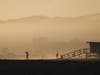 People gather as the sun sets on the mostly empty Venice Beach, with the shuttered Santa Monica Pier (Lower L) in the background, amid the COVID-19 pandemic on Independence Day on July 4, 2020 in Venice, California. 