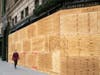 A person walks by a boarded up Saks Fifth Avenue on November 1, 2020 in New York City. Businesses have taken to boarding up store fronts in anticipation of unrest related to the presidential election.
