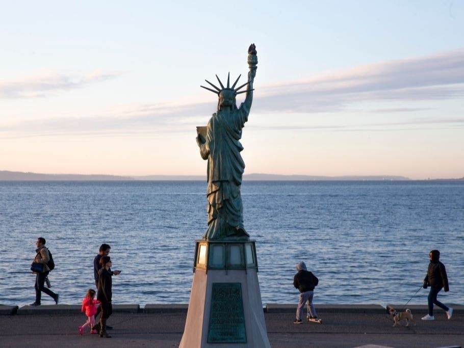 People enjoy the fresh air in front a Statue of Liberty replica statue at Alki Beach Park on March 20, 2020 in Seattle
