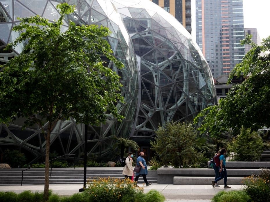 People wearing masks walk by The Spheres at the downtown Amazon campus on April 30, 2020, in Seattle.